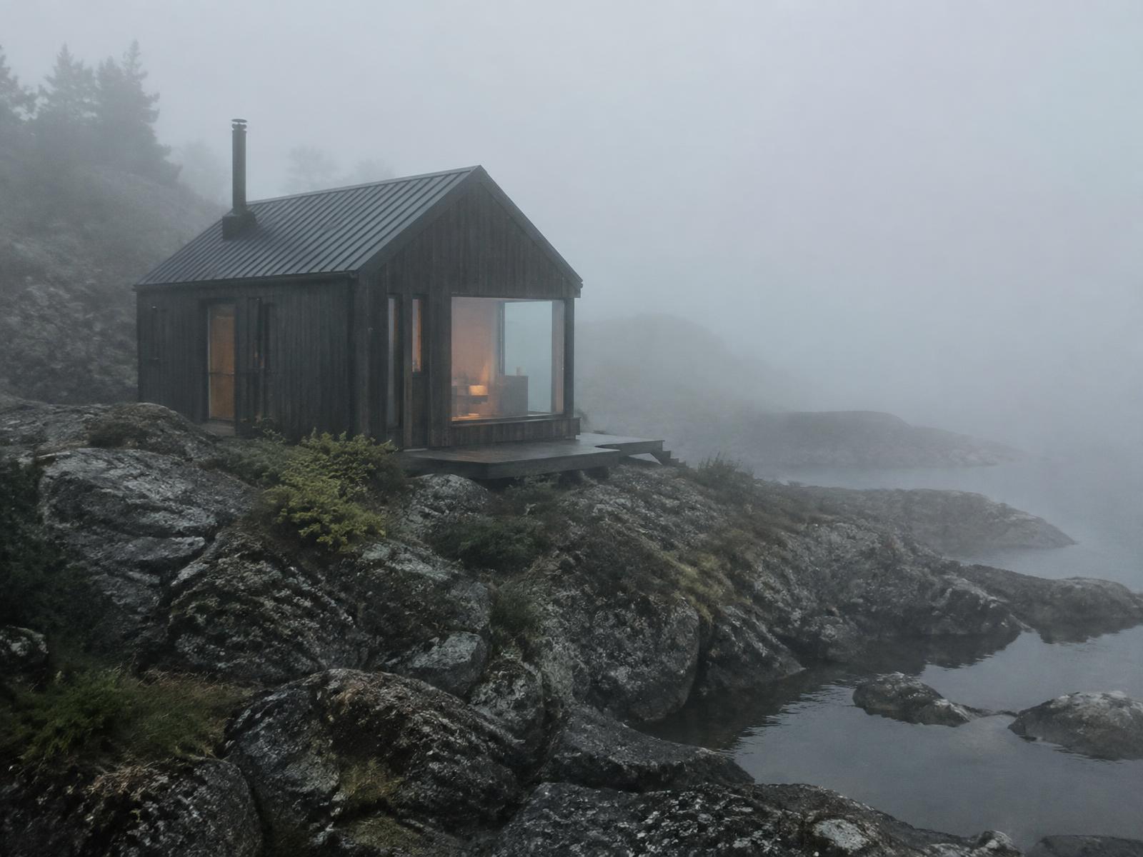 Small dark timber cabin isolated on a rocky coast wrapped in dense sea fog, rendered in Blender with Cycles X